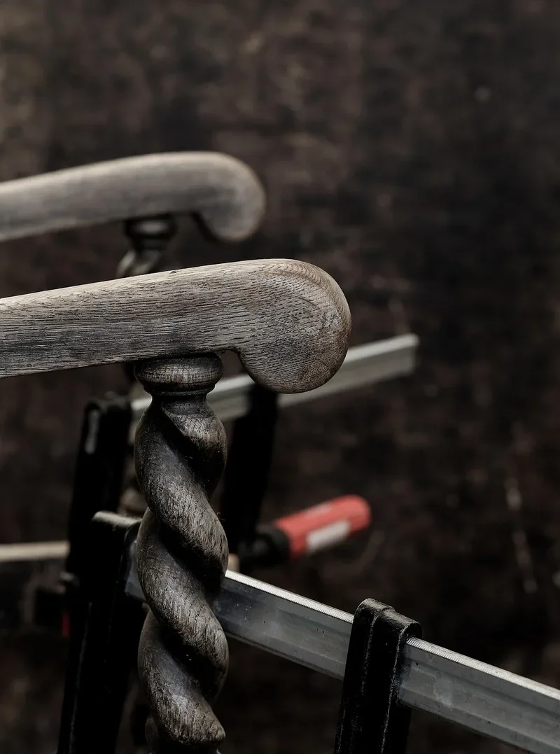 Antique oak chair parts held under bar clamps while glue cures