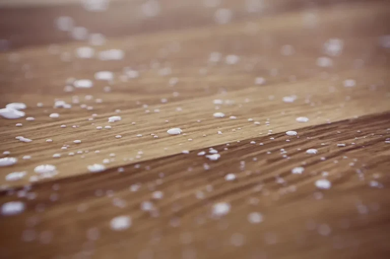 White wood glue droplets on an oak board surface