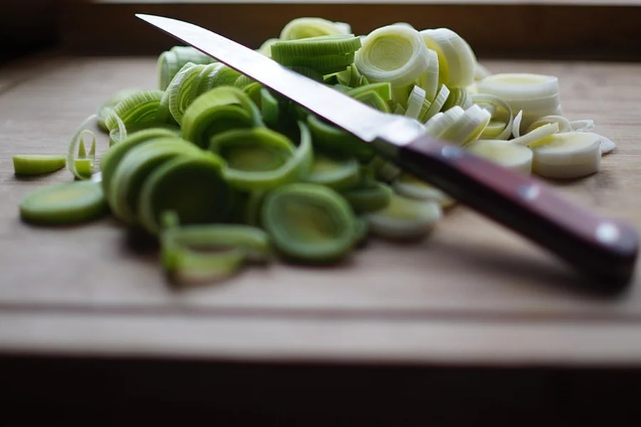 Kitchen knife resting on a wooden cutting board after chopping vegetables