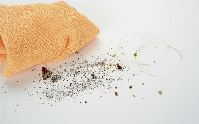 Orange microfiber cloth wiping crumbs and dust off a clean surface Orange microfiber cloth wiping crumbs and dust off a clean surface