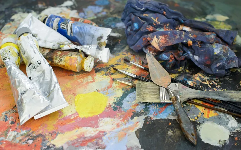 painter cleaning a brush with solvent in a workshop after oil-based paint application