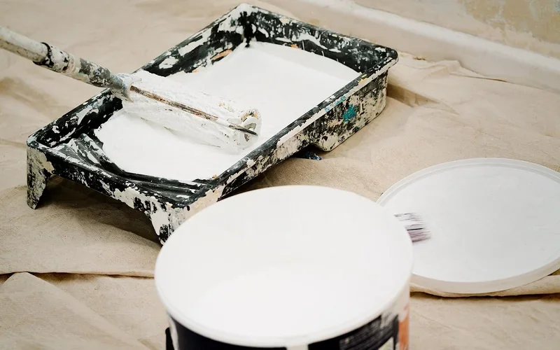 Paint tray and roller with white paint on a drop cloth