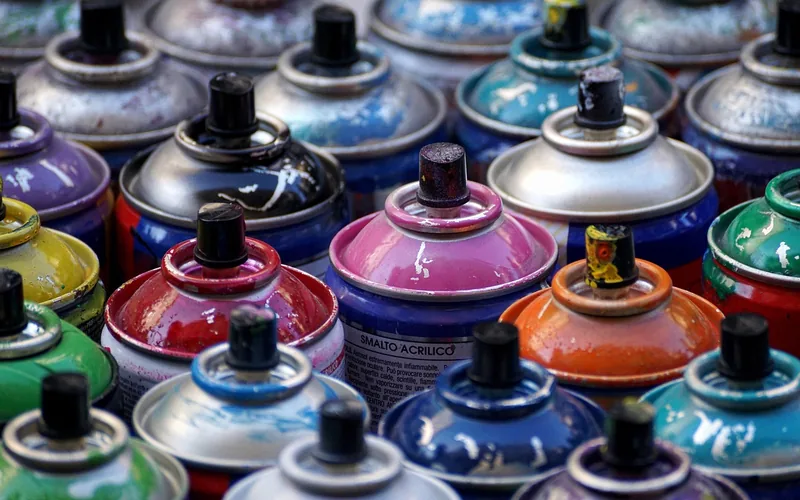 paint and spray cans stored on a workshop shelf -- solvents require sealed containers away from heat sources