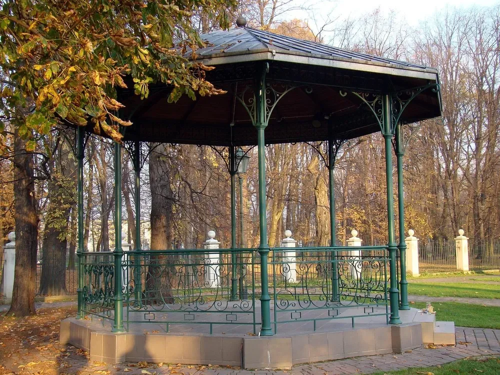 Painted green metal gazebo with decorative ironwork in a park