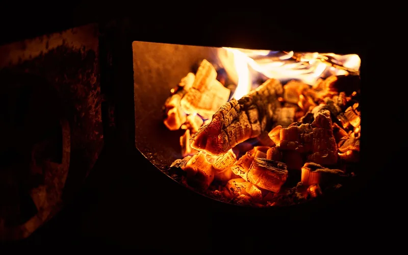 wood smoldering inside a smoker producing thin smoke over hot coals wood smoldering inside a smoker producing thin smoke over hot coals