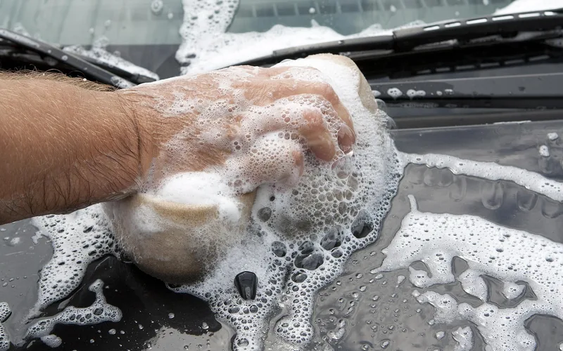 sponge and soapy water washing a car exterior and windows