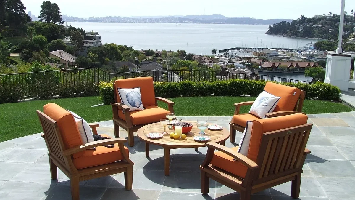 Solid teak patio armchairs and round table on a stone terrace