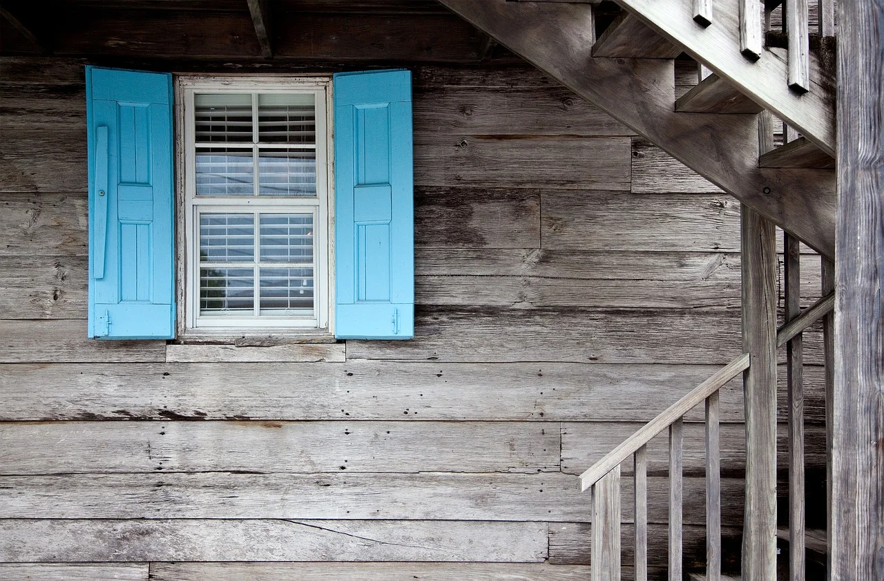 weathered gray wood siding with peeling blue shutters in need of a fresh exterior paint coat weathered gray wood siding with peeling blue shutters in need of a fresh exterior paint coat
