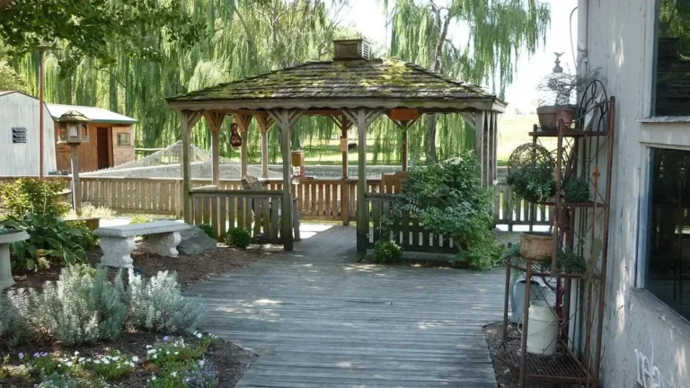 Weathered wooden gazebo with a shingle roof on a backyard deck