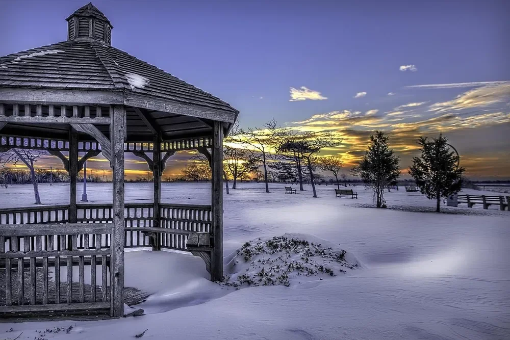 Wooden gazebo standing in deep snow at sunset