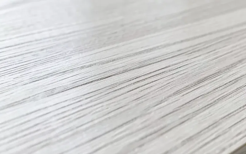 Close-up of pale ash wood grain texture on a sanded board showing straight grain pattern