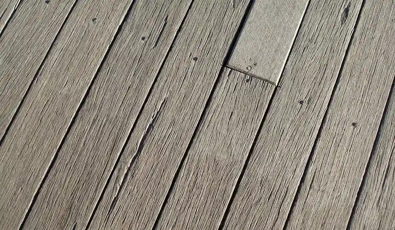 Weathered gray cedar deck boards showing UV surface checking and graying Weathered gray cedar deck boards showing UV surface checking and graying