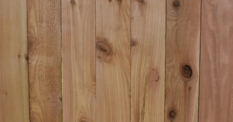 Close-up of cedar fence boards showing reddish heartwood grain and knots