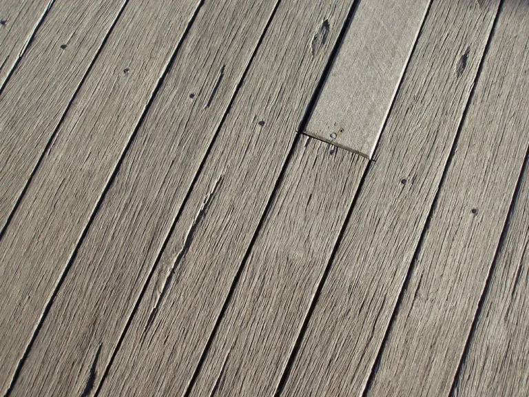 Close-up of weathered deck boards in direct sunlight showing surface heat exposure