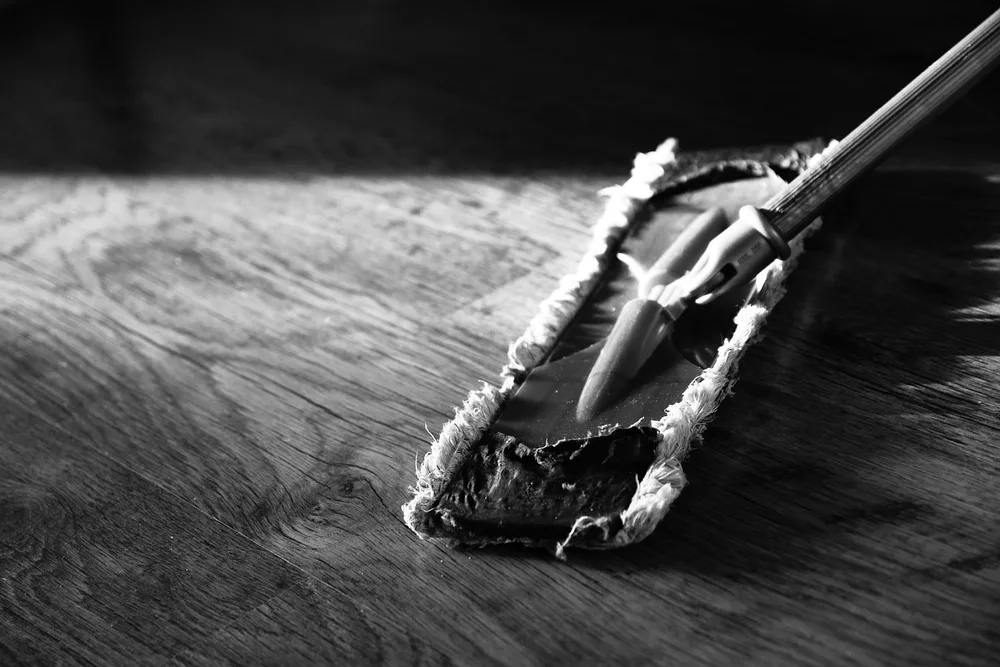 Flat dust mop gliding across an oak plank floor