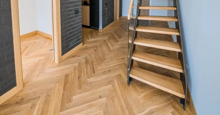 Newly installed oak herringbone hardwood floor beside a staircase