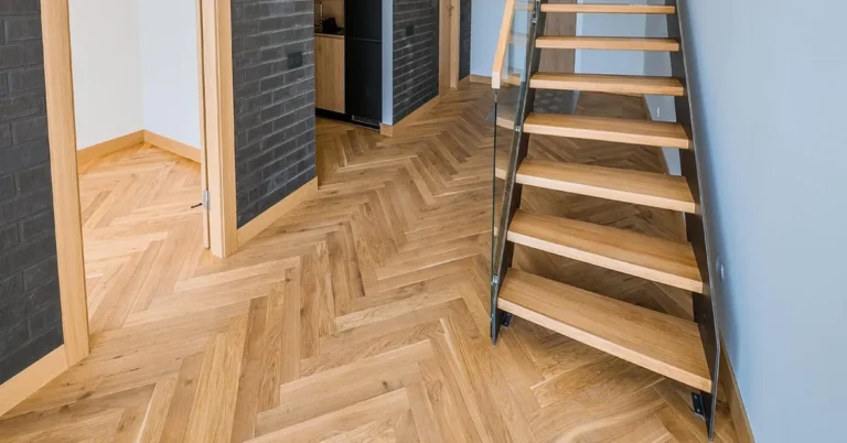 Herringbone oak hardwood floor in a finished room beside an open staircase