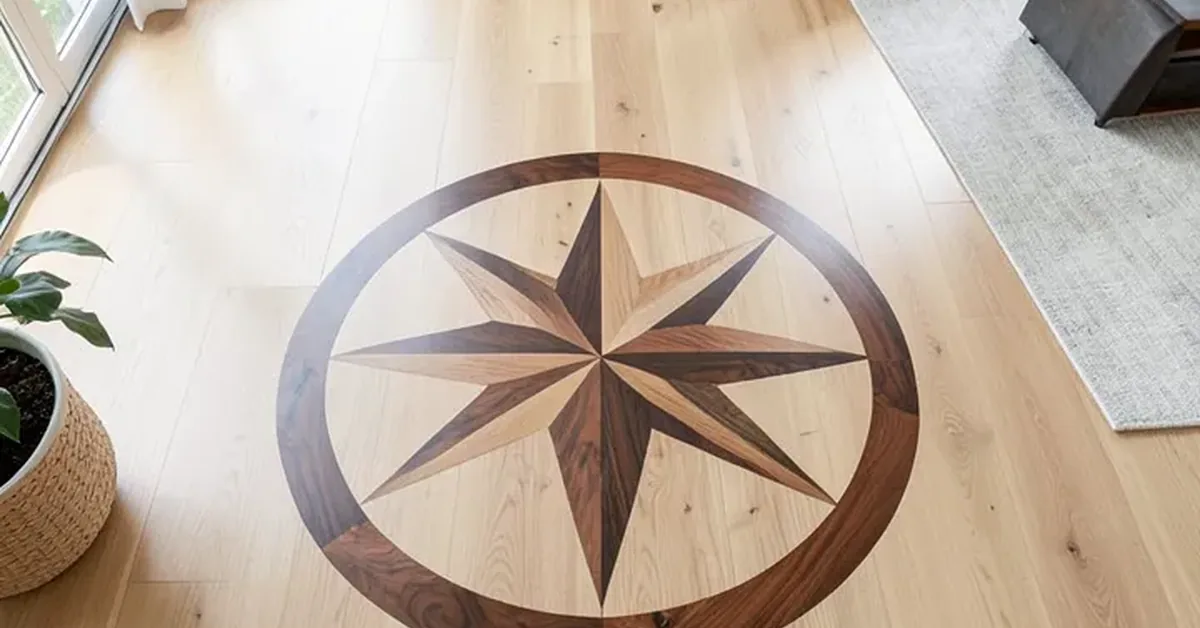 Circular walnut and oak compass star wood inlay medallion set into a light oak hardwood floor