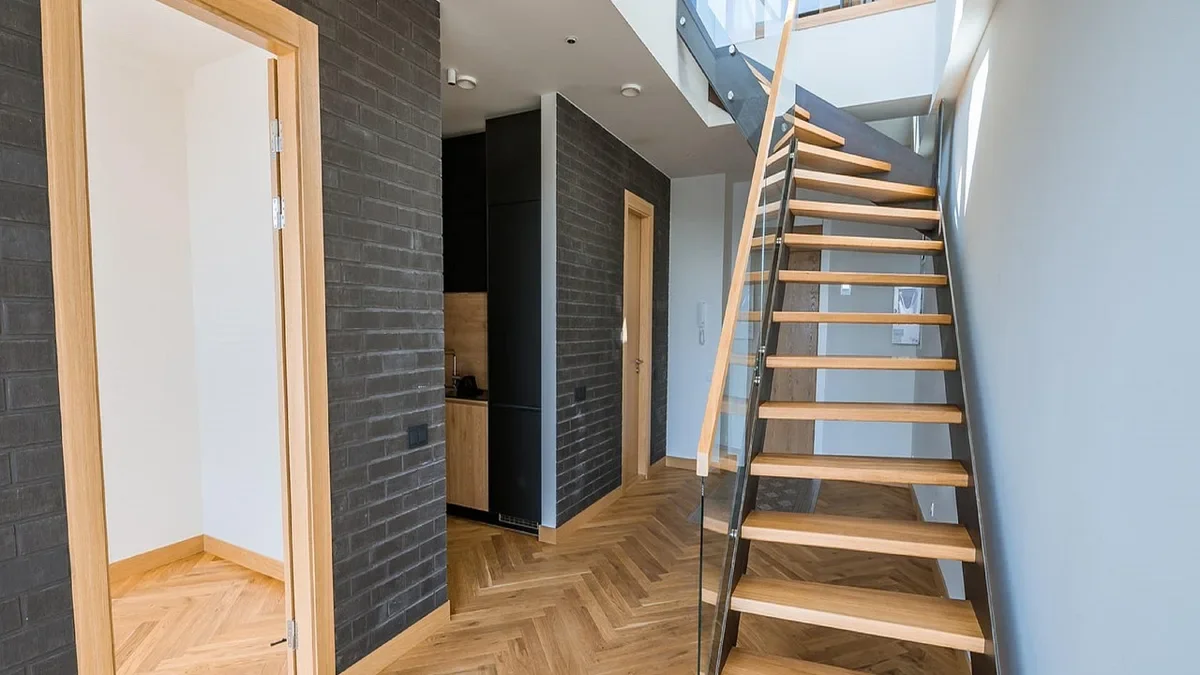 Oak herringbone hardwood floor in a bright hallway with a stair