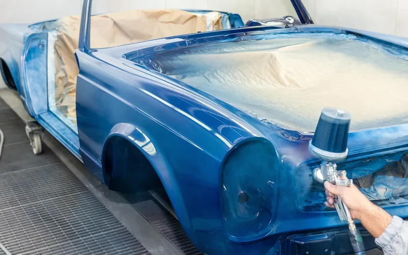 HVLP spray gun applying a fine mist of paint to a car body panel