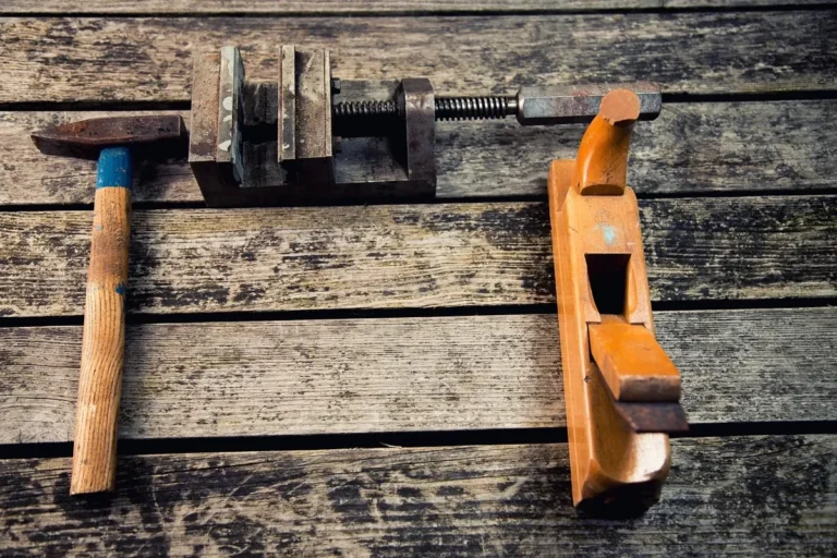 Hammer, vise and wooden plane on a weathered workshop bench