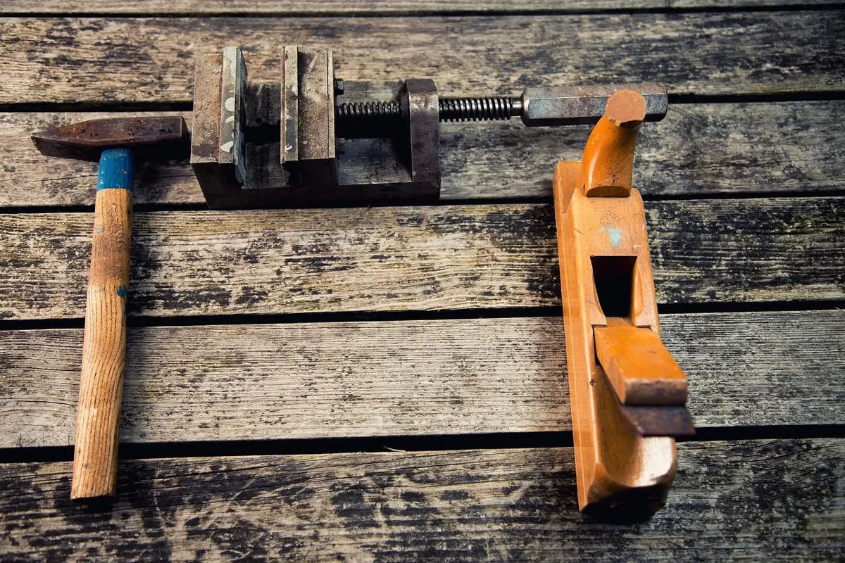 Hammer, vise and wooden plane on a weathered workshop bench