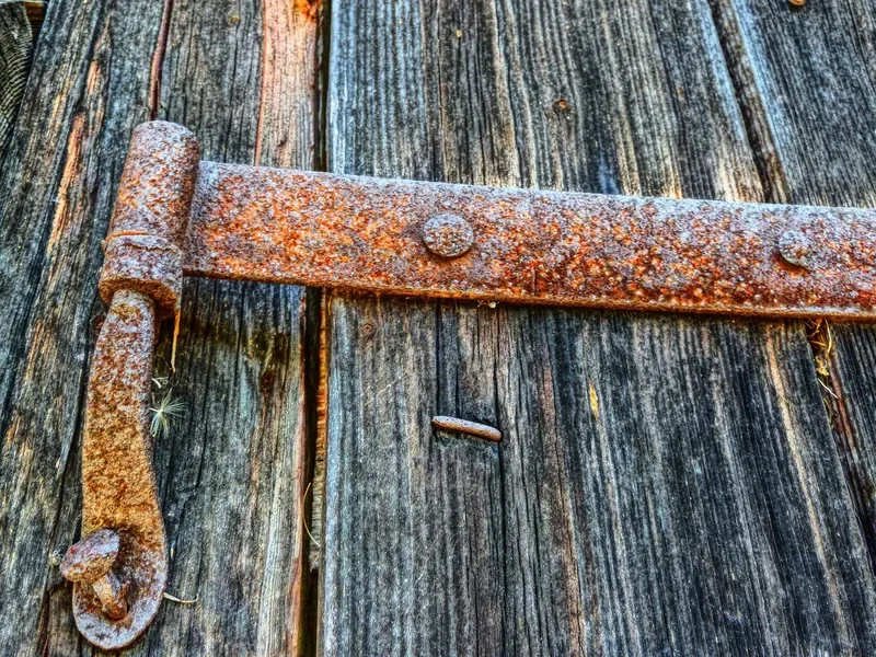 Rusty iron strap hinge on weathered wood, the kind of heavy corrosion tumbling media will not fully remove Rusty iron strap hinge on weathered wood, the kind of heavy corrosion tumbling media will not fully remove