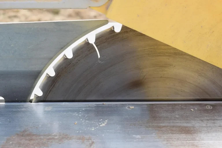 Table saw blade teeth and splitter area on a cast iron saw table