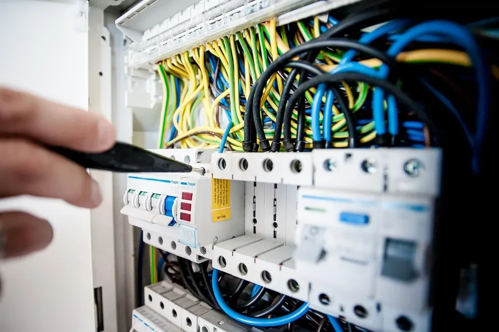Hand at an electrical breaker panel, the kind of panel to check before adding a 230V saw circuit