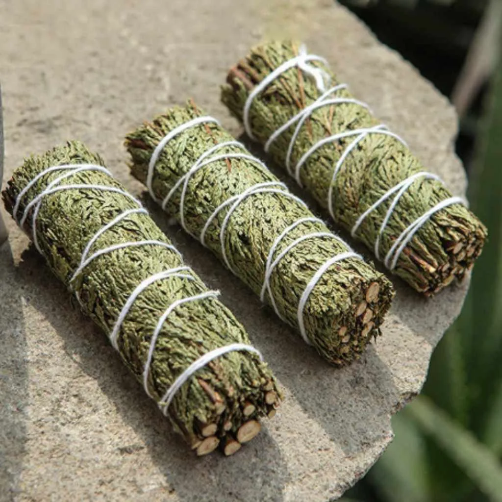 three cedar smudge sticks laid out on stone three cedar smudge sticks laid out on stone