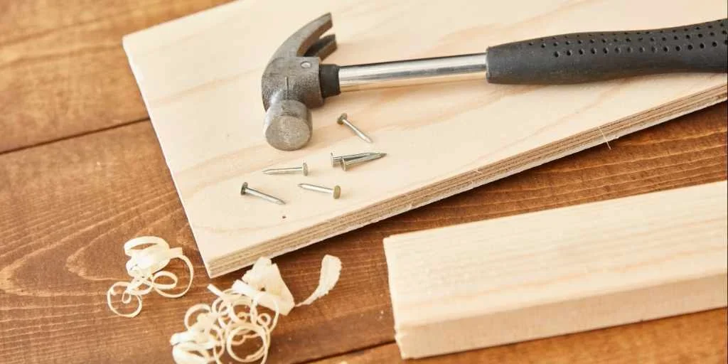 Stack of plywood sheets with a close-up of a birch panel edge and hammer
