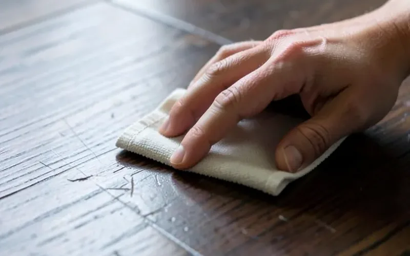 Buffing out a light hardwood scratch Hand buffing and touching up light scratches on a dark hardwood floor with a cloth