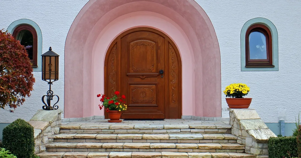 Stained solid wood arched entry door with a warm brown finish