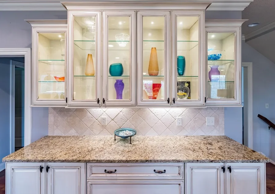 Glazed white kitchen cabinets with glass-front upper doors and black pulls