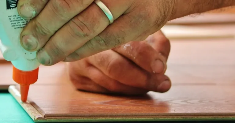 Hand applying a bead of wood glue along the edge of a board before assembly