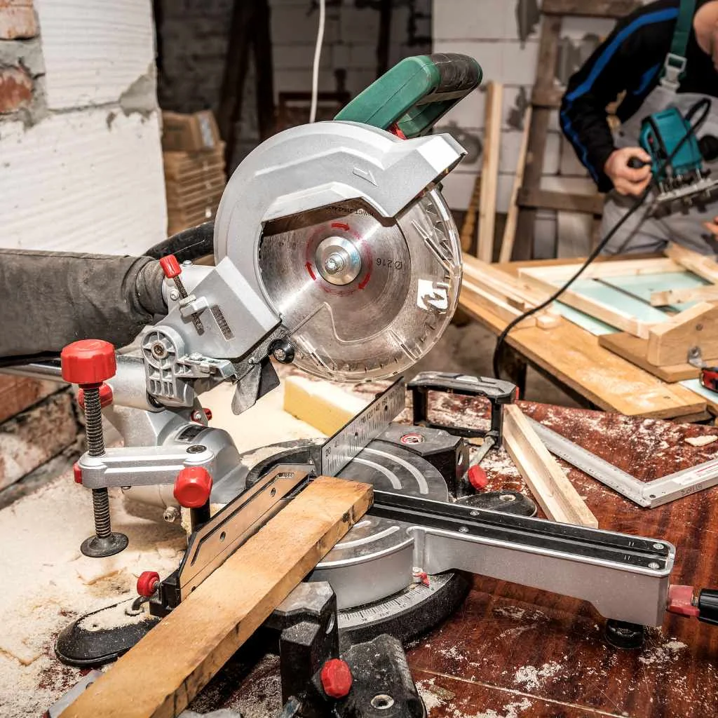 A miter saw clamped and set up in a home workshop