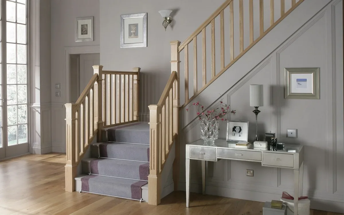 Light oak staircase with turned balusters and a carpet runner in a home entrance hall