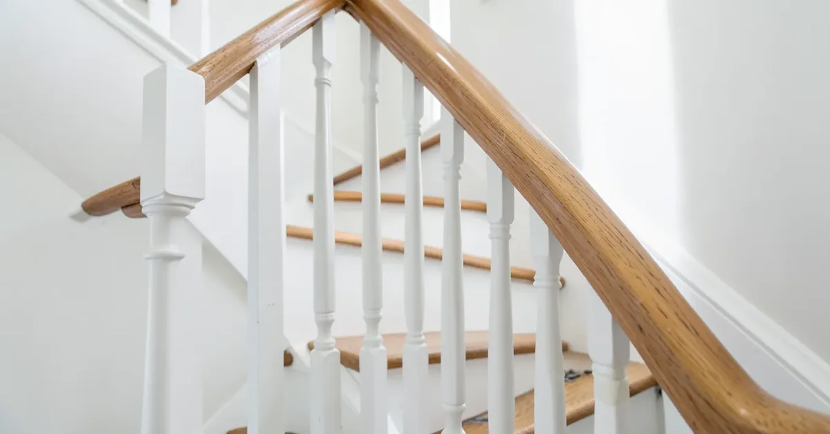Freshly painted white staircase spindles next to a natural wood handrail