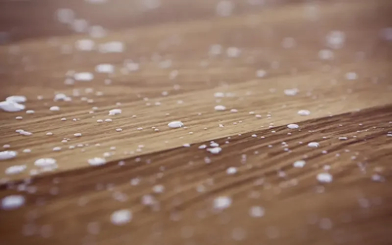 White glue droplets scattered on a wood board surface