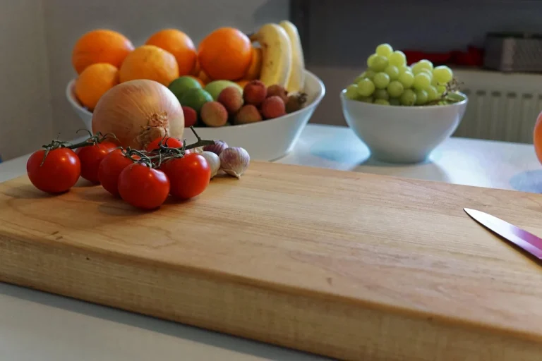 Wood cutting board with fresh tomatoes and a knife on a kitchen counter