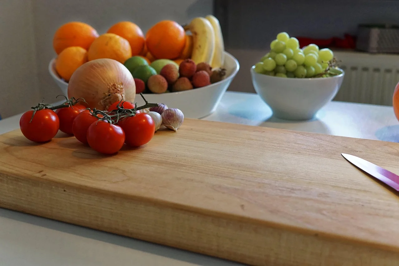 Wood cutting board with fresh tomatoes and a knife on a kitchen counter