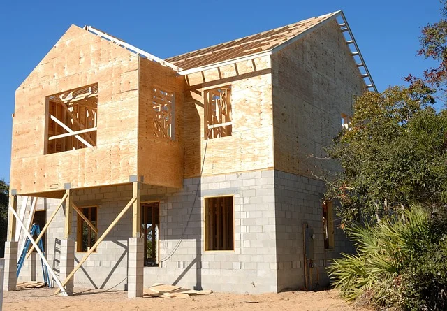 Two-story wood frame house under construction with stud walls and roof framing