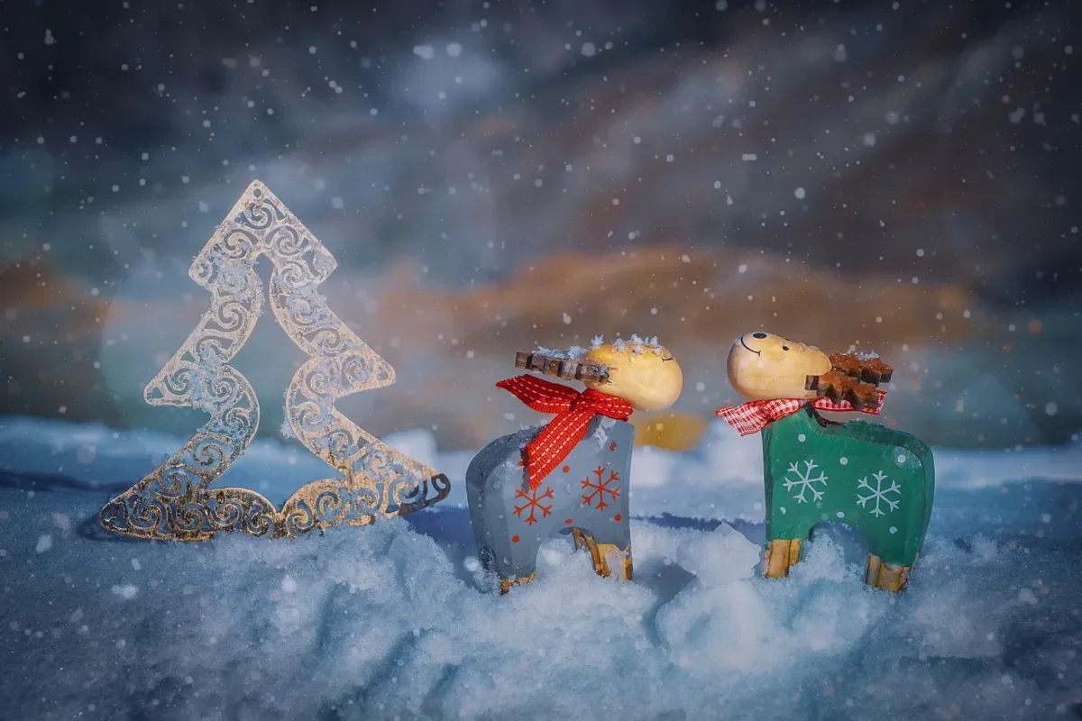 Two painted wooden reindeer figures standing in snow