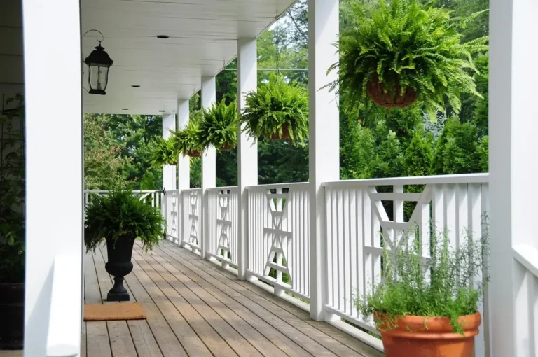 White painted wood porch deck with railing and potted plants