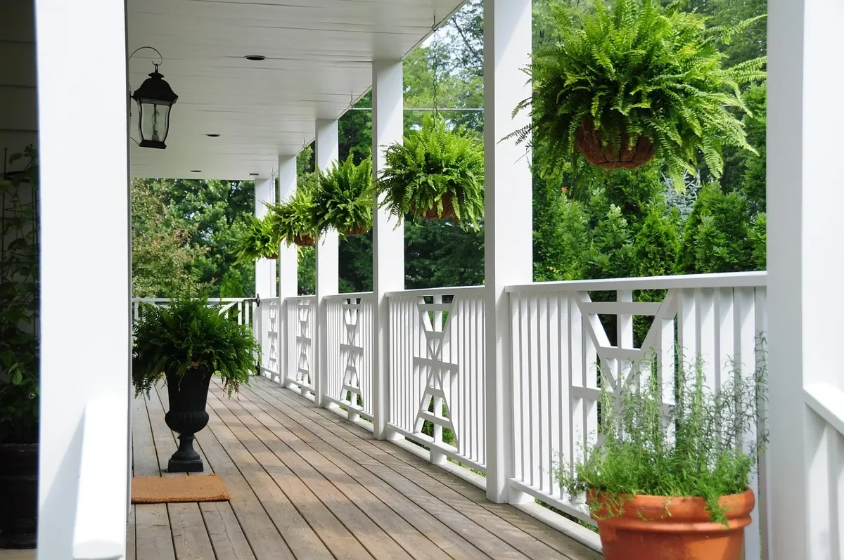 White painted wood porch deck with railing and potted plants