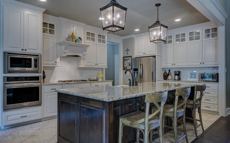 White painted kitchen cabinets next to a dark stained wood island