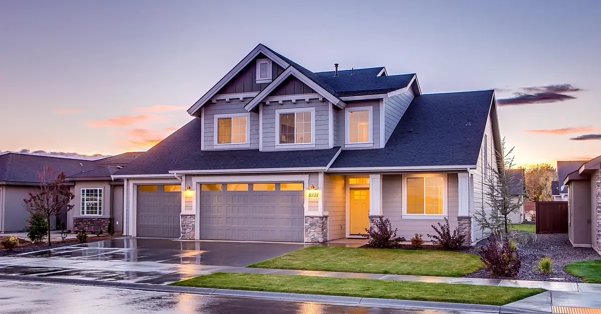 freshly painted gray garage doors on a two-story house with stone accents