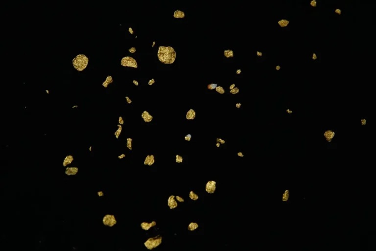Gold glitter flakes scattered on a dark background