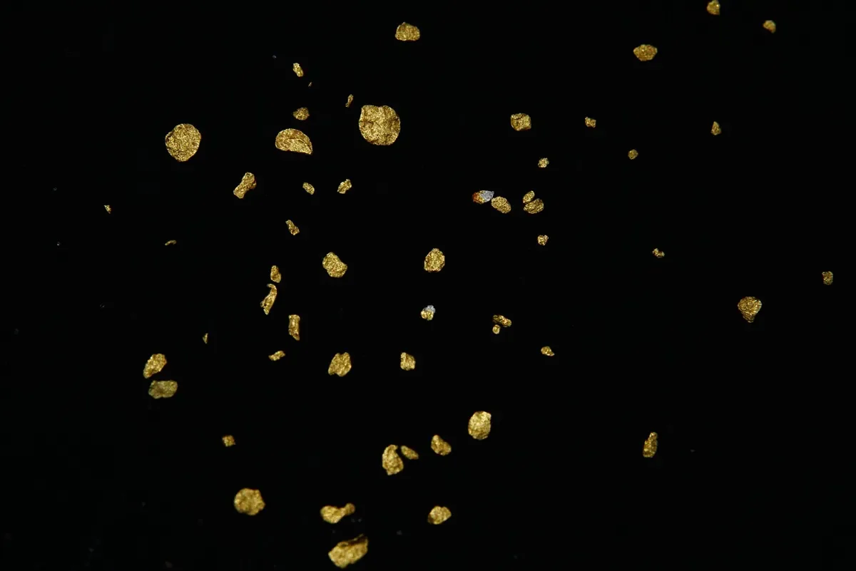 Gold glitter flakes scattered on a dark background