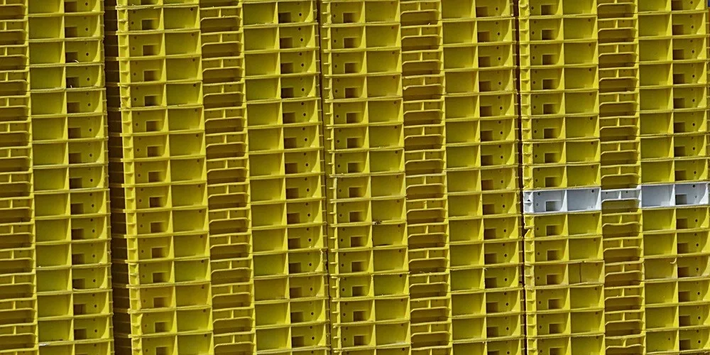 Stacked yellow molded plastic crates, the kind of slick polyethylene plastic that resists most glues